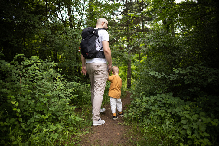 father walking in woods with child