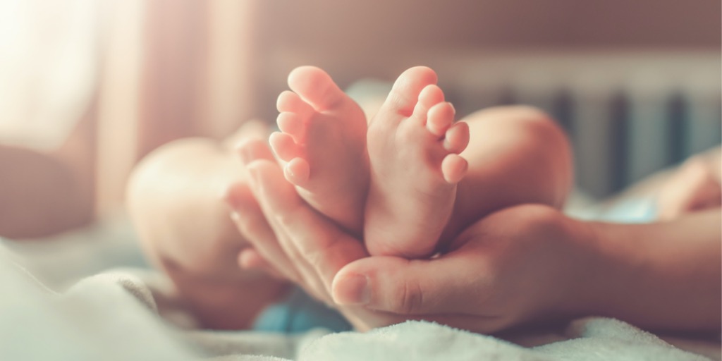 feet of new born baby in hand